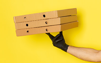 A man holding three printed pizza boxes stacked