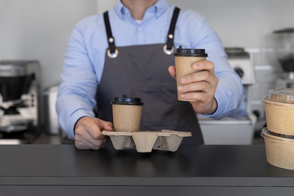 man with apron preparing coffee takeaway