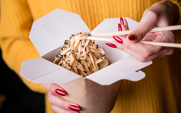 Girl eating noodles from takeout container