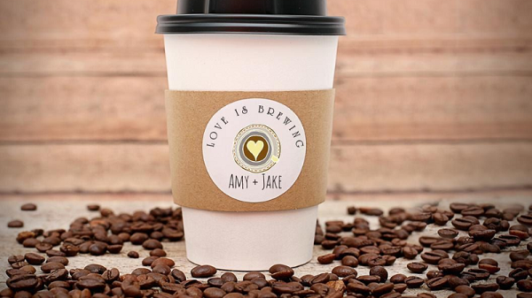 A coffee cup with logo in center and coffee beans spilled around the cup