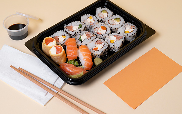 Takeout sushi tray with chopsticks and a container of soy sauce