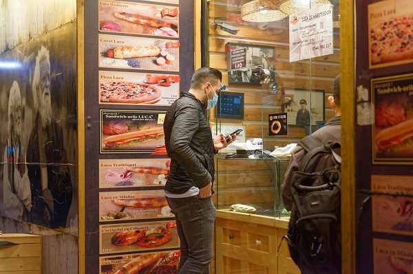 Customers are waiting for customized pizzas in front of the pizzeria.