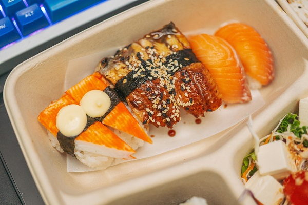 A brown bagasse container full of sushi