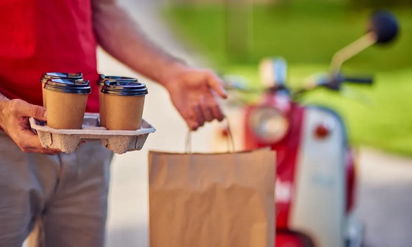 A delivery man is delivering coffee takeout