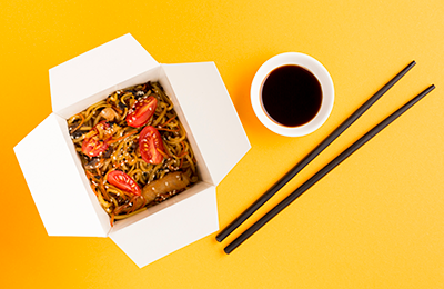 Chinese takeout box infront of yellow background.png