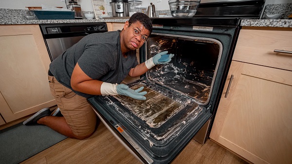 A man is checking and cleaning the oven.