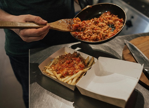 Chefs are packing food into disposable takeout boxes.