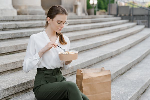 A woman eating lunch out of disposable takeout container.